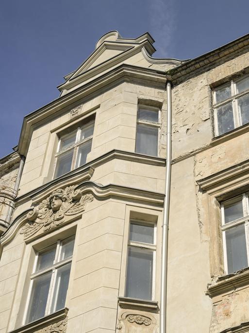 Ausschnitt eines Berliner Mietshauses. Die Fassade und die Fenster sind alt. Es ist erkennbar, dass schon lange nichts mehr an dem Haus gemacht wurde.