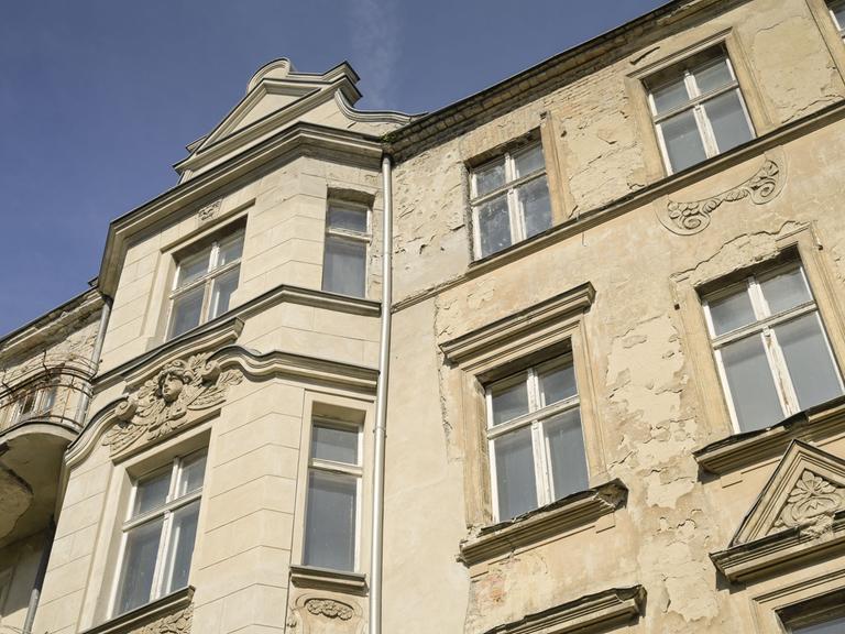 Ausschnitt eines Berliner Mietshauses. Die Fassade und die Fenster sind alt. Es ist erkennbar, dass schon lange nichts mehr an dem Haus gemacht wurde.