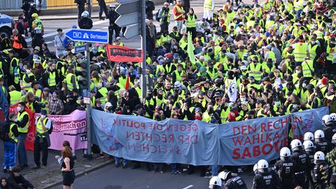 Zahlreiche Demonstranten stehe oder sitzen auf einer Straße in Essen. Sie tragen gelbe Westen. Rechts im Vordergrund stehen Polizisten. 