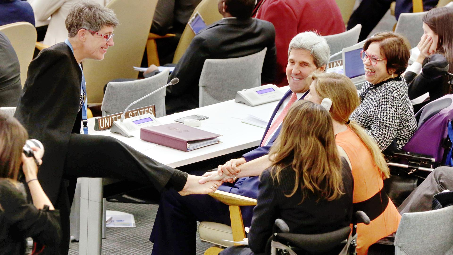Theresia Degener (links) begrüsst den damaligen U.S. Secretary of State John Kerry und die U.S. Botschafterin bei den Vereinten Nationen Samantha Power mit ihrem rechten Fuß. 