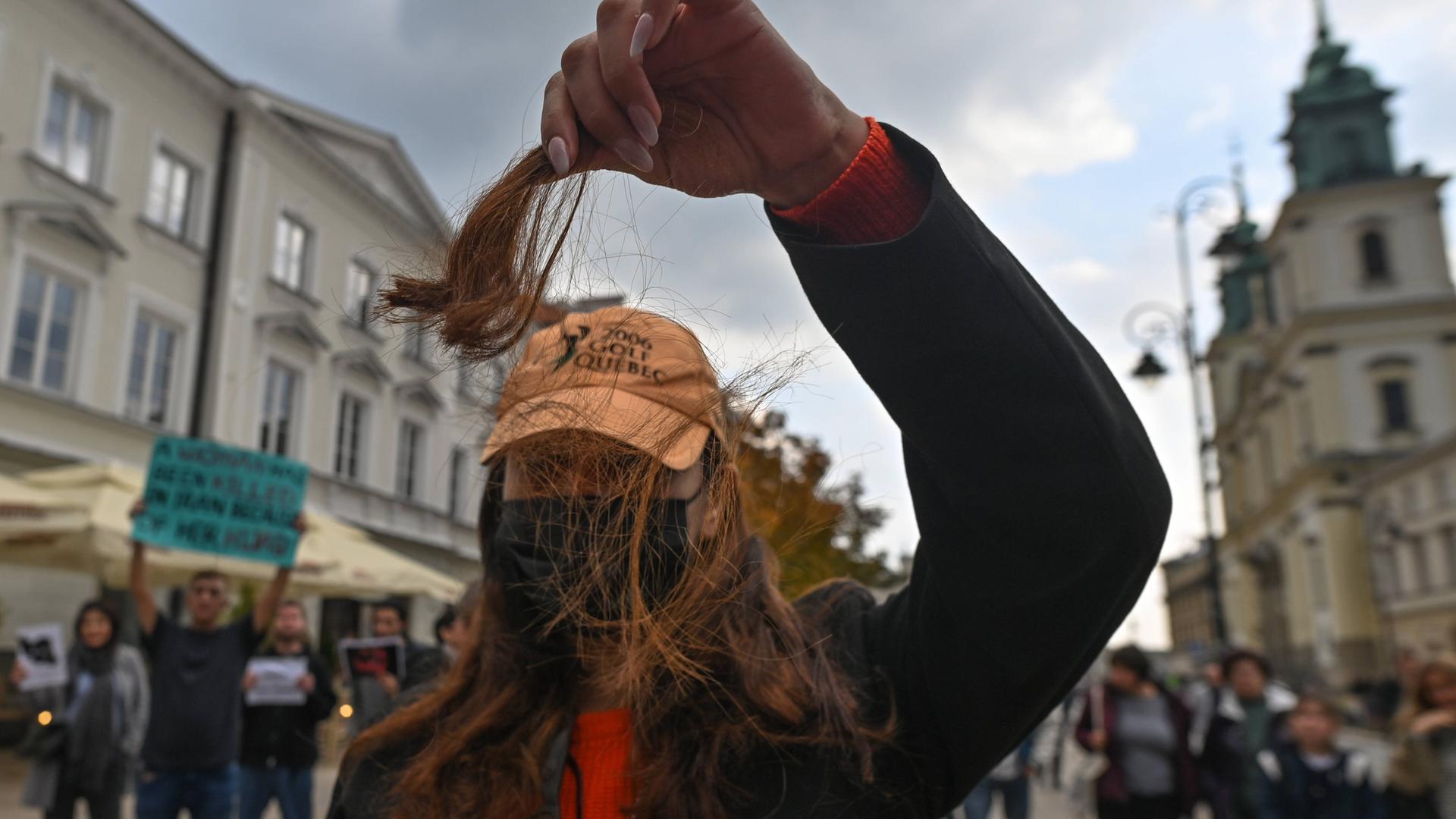 Eine Frau hält bei einer Demonstration eine abgeschnittene Haarsträhne hoch. Eine Frau hält bei einer Demonstration eine abgeschnittene Haarsträhne hoch.