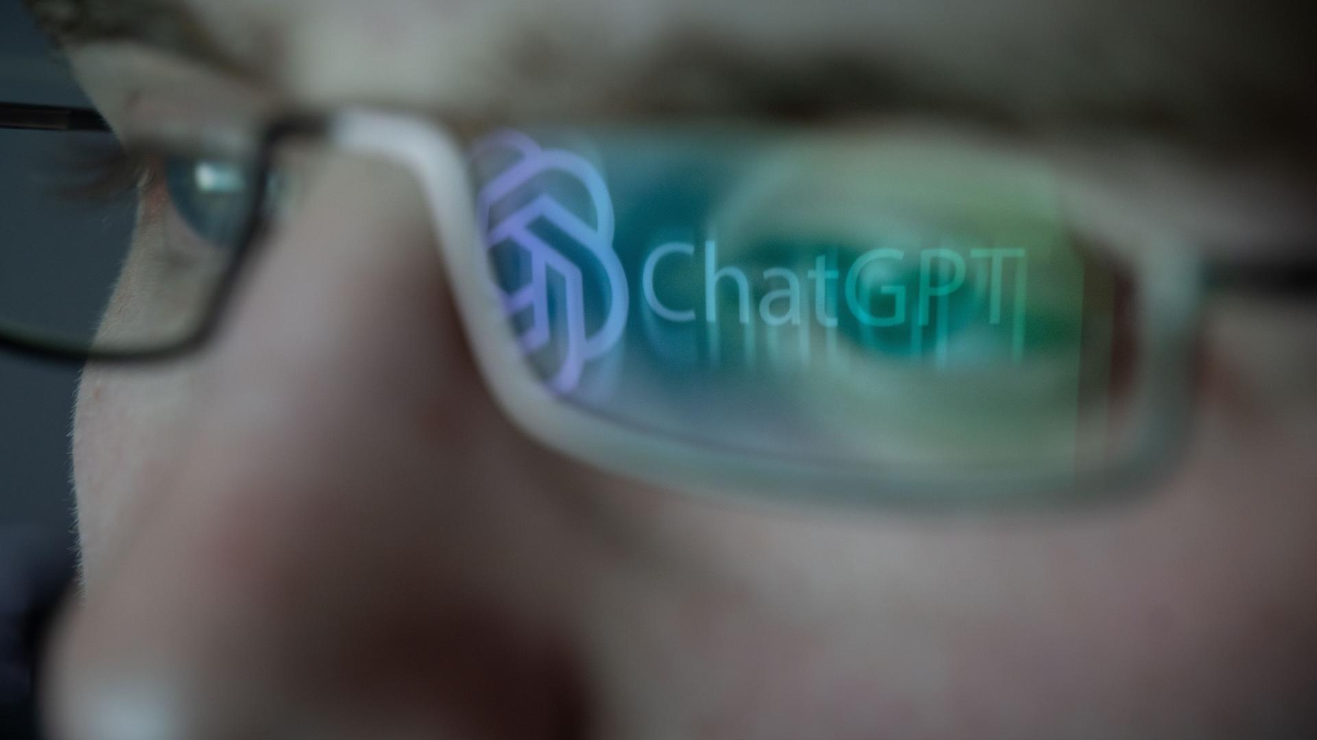 In der Brille eines Mannes spiegelt sich das Logo von ChatGPT. 