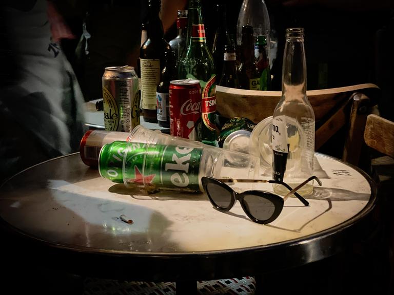 Auf einem runden Tisch stapeln sich Flaschen, Bierdosen und leere Getränkebecher.