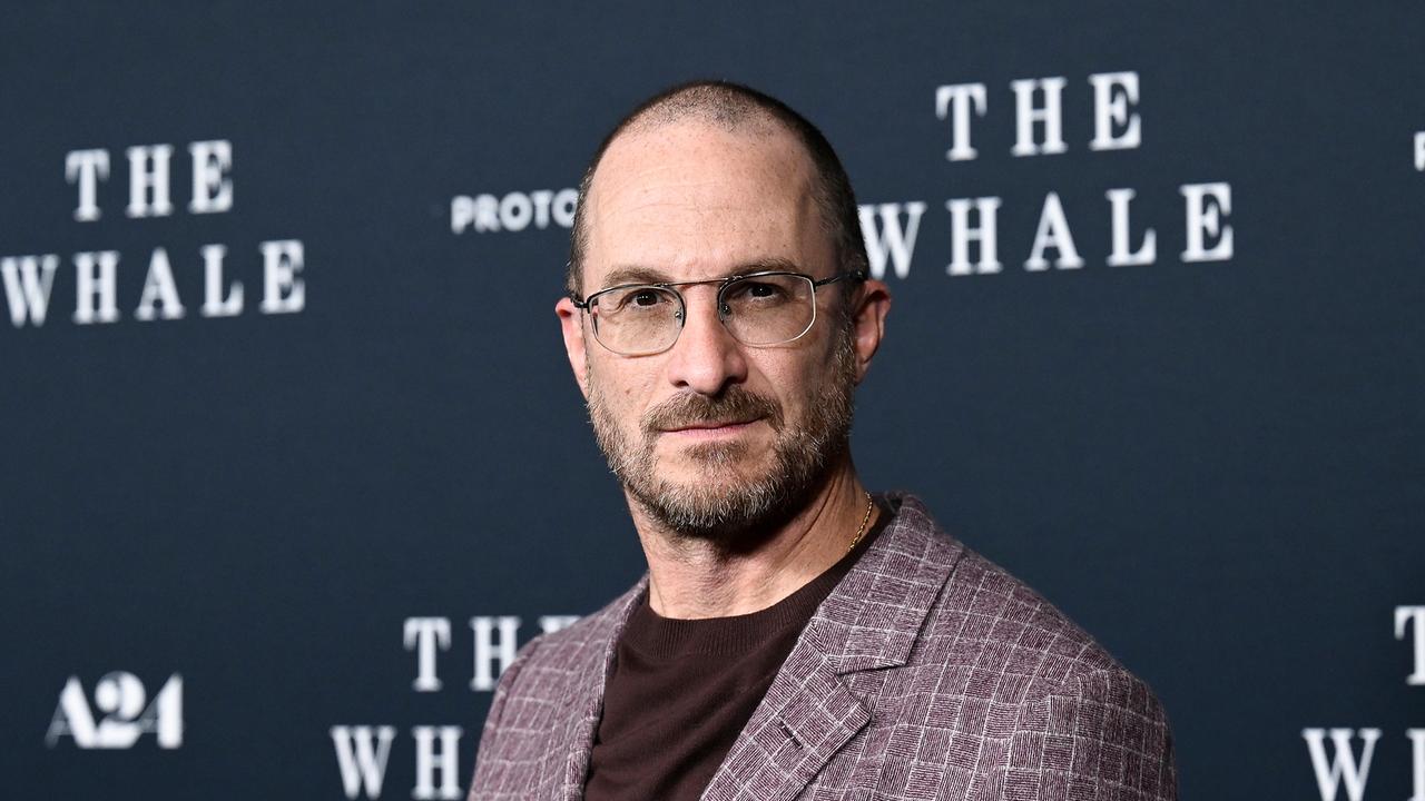 Das Bild zeigt Darren Aronofsky vor einer Wand mit der Aufschrift "The Whale", dem Titel einer seiner Filme.