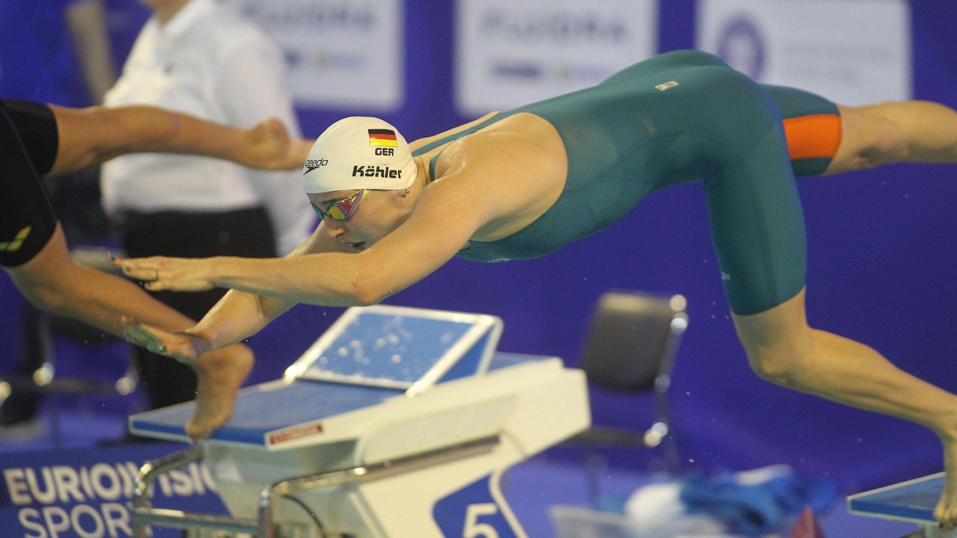 Schwimmerin Angelina Köhler springt vom Startblock ins Wasser.