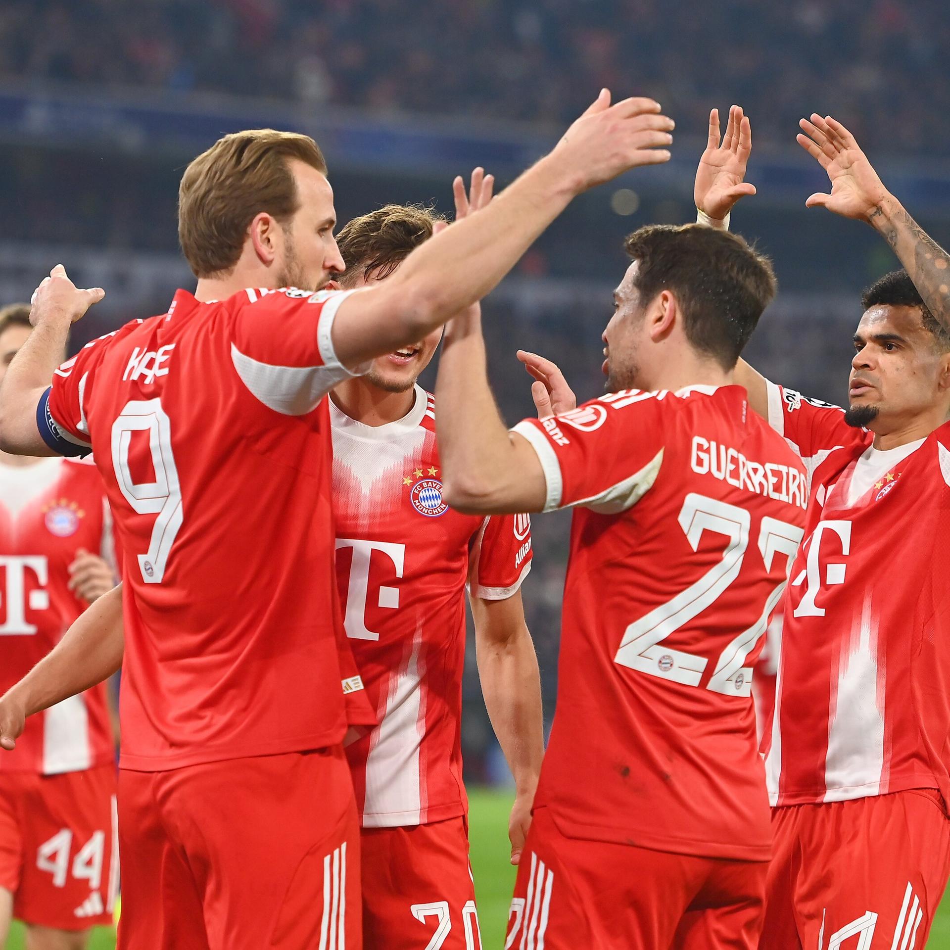 Bayern-Spieler in roten Trikots klatschen jubelnd ab.
