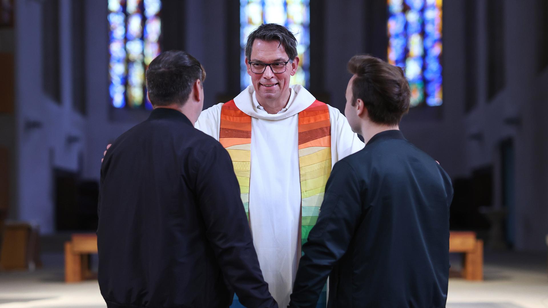 Pfarrer Christoph Kunz (M) segnet während einer Segnungsfeier das queere Paar Falko (l) und DennÃ©s (r) in der Bischofskirche Sankt Sebastian des katholischen Bistums Magdeburg. Offiziell sind Segnungen gleichgeschlechtlicher Paare in der katholischen Kirche verboten, weil dem Vatikan zufolge nur Heterosex in der Ehe von Gott gewünscht ist. Dagegen gibt es bei den deutschen Katholiken aber breiten Widerstand.