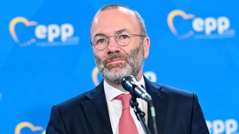 Manfred Weber steht vor einem Mikrofon. Hinter ihm eine blaue Wand mit dem Logo der EVP-Fraktion.