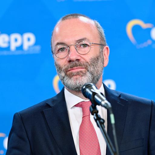 Manfred Weber steht vor einem Mikrofon. Hinter ihm eine blaue Wand mit dem Logo der EVP-Fraktion.
