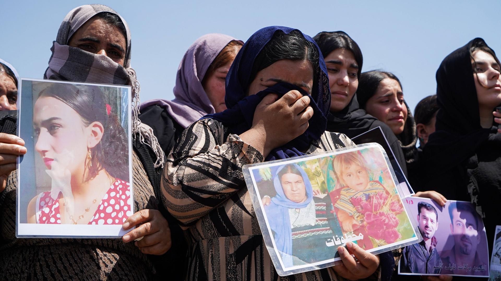 Trauerzeremonie im Lager Chamishko (Region Kurdistan im Irak) anlässlich des 10. Jahrestags des Völkermords an den Jesiden im August 2024.  Weinende Frauen halten Fotos von vermissten Angehörigen in den Händen.  
