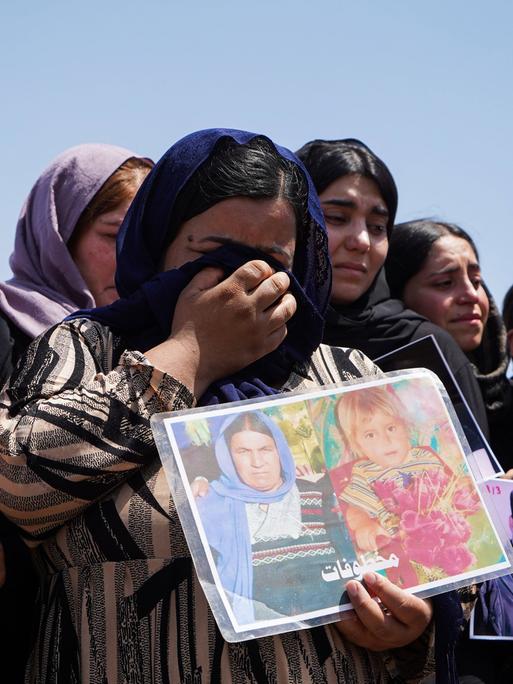 Trauerzeremonie im Lager Chamishko (Region Kurdistan im Irak) anlässlich des 10. Jahrestags des Völkermords an den Jesiden im August 2024.  Weinende Frauen halten Fotos von vermissten Angehörigen in den Händen.  