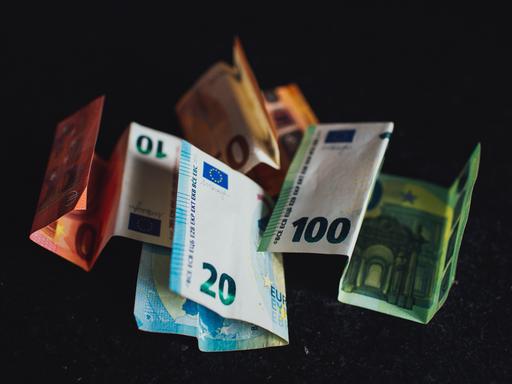 Fallende Geldscheine vor schwarzem Hintergrund