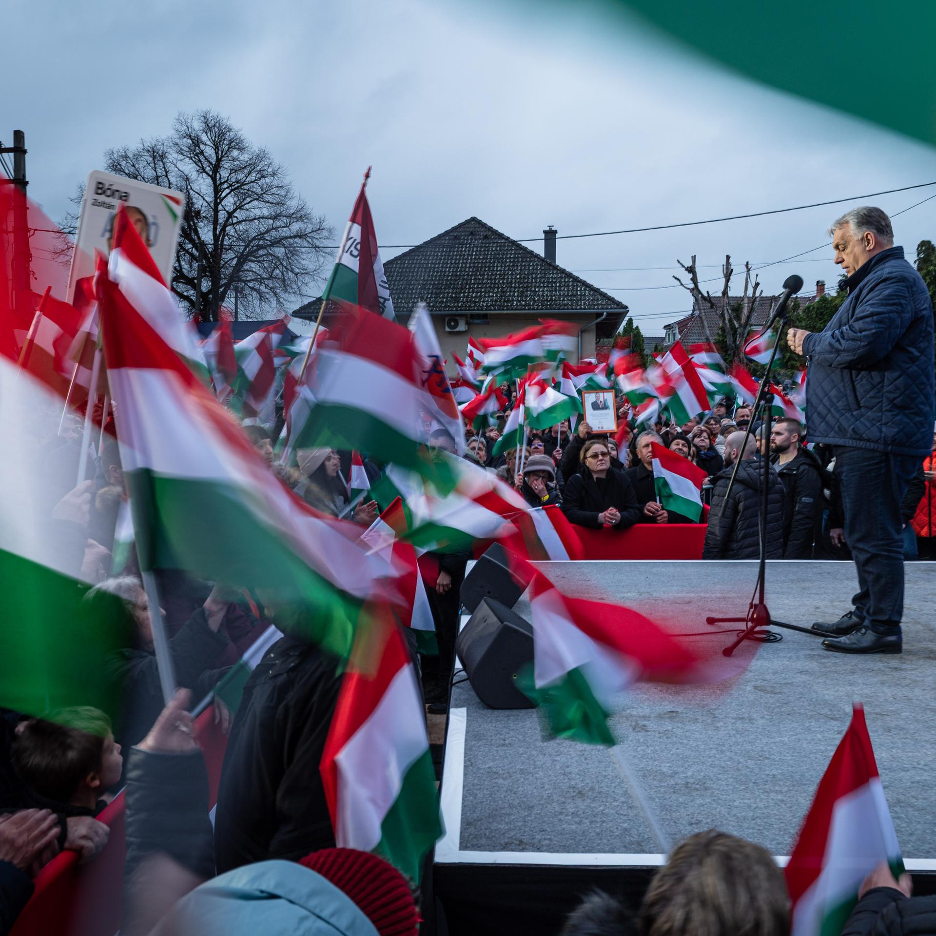 Viktor Orban steht in Ocsa während einer Wahlkampfveranstaltung auf der Bühne, um ihn herum Anhänger mit Fahnen.