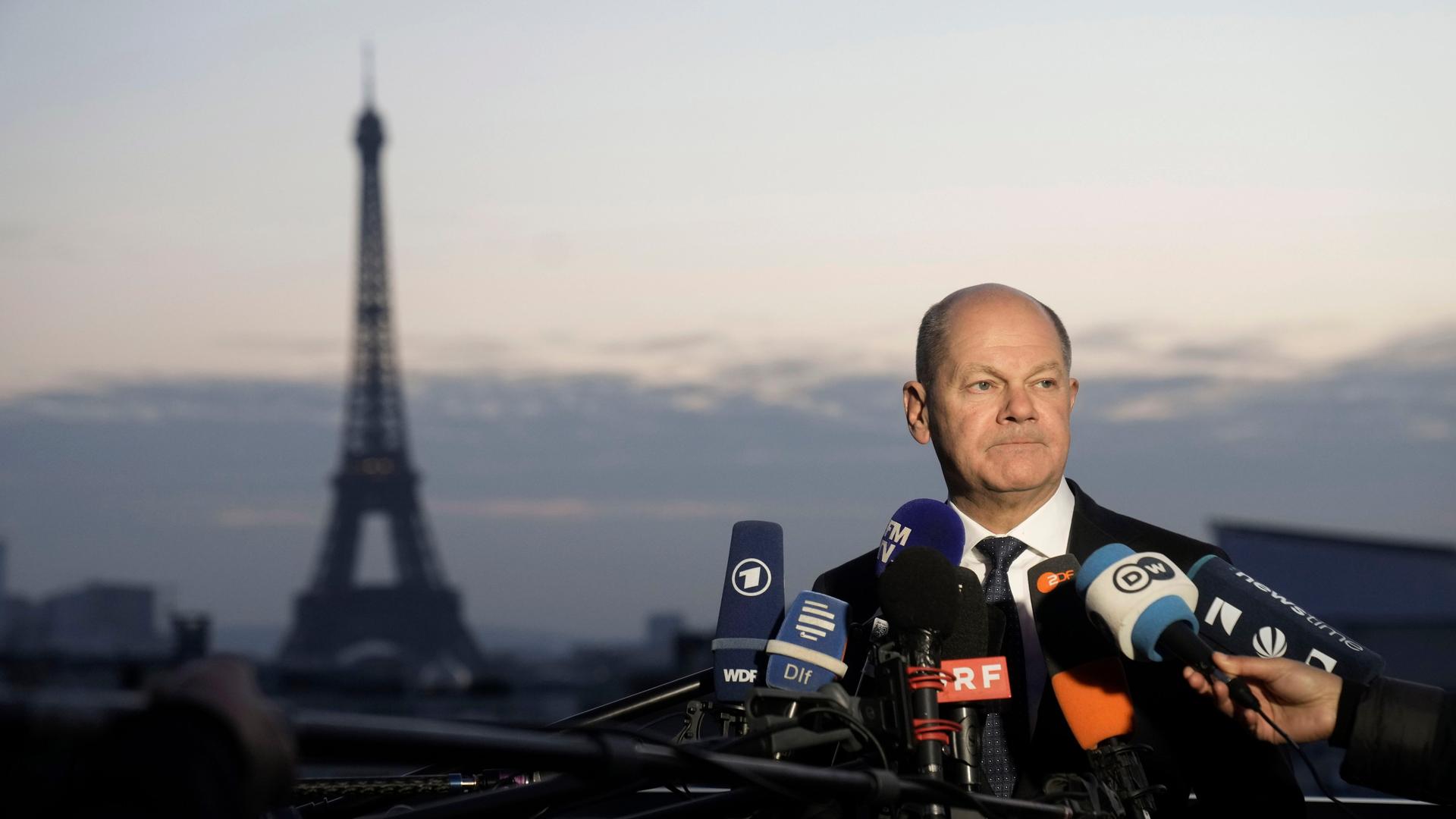 Bundeskanzler Olaf Scholz spricht mit Medienvertretern in Paris. Im Hintergrund ist der Eiffelturm zu sehen.