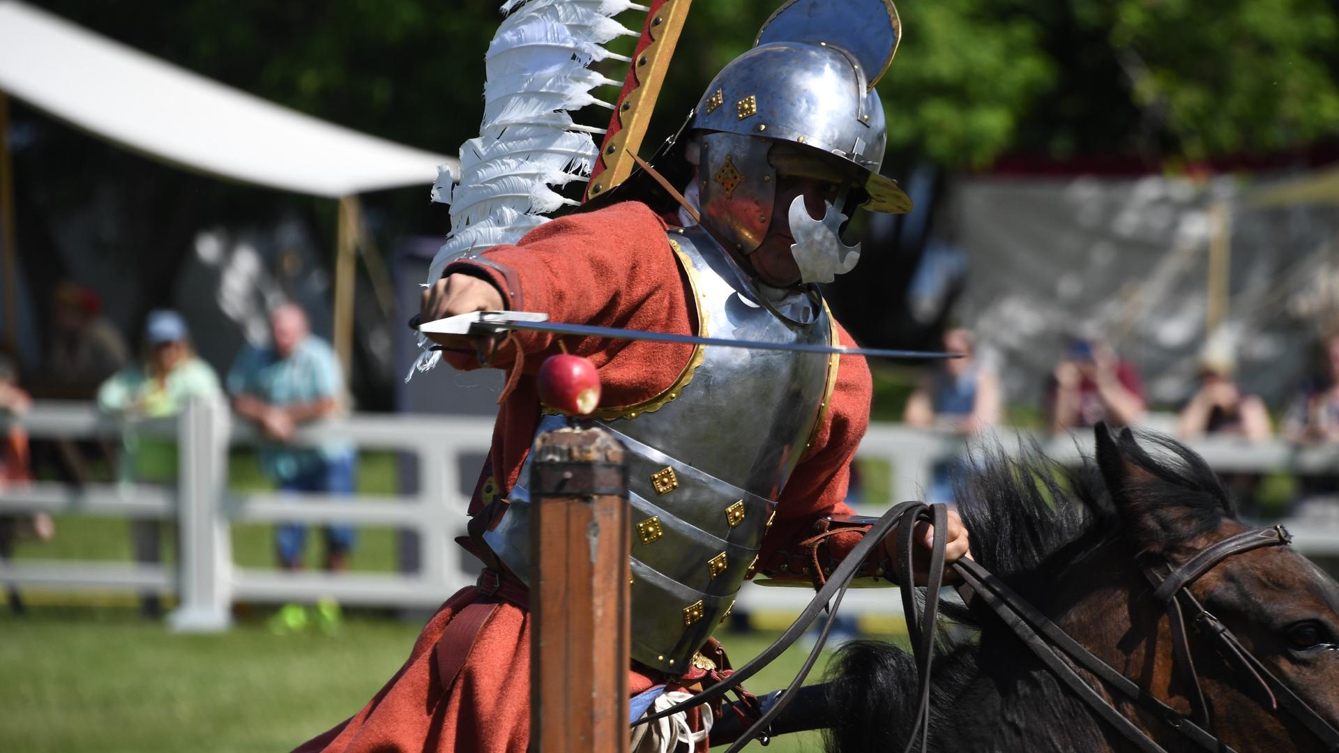 Teilnehmer eines Mittelalter-Festes in Ritterrüstung auf einem Pferd.