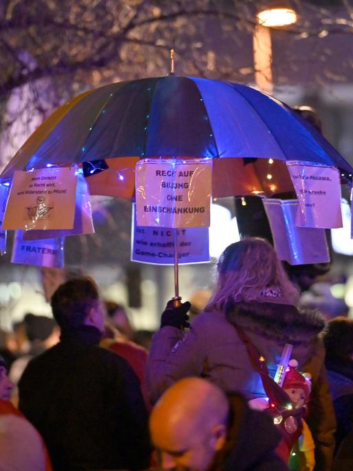 Montagsspaziergang von Gegnern der Corona-Politik und Impfverweigerern. Demonstranten mit einem dekorierten Schirm. 