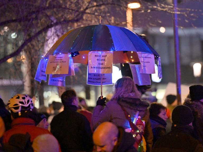 Montagsspaziergang von Gegnern der Corona-Politik und Impfverweigerern. Demonstranten mit einem dekorierten Schirm. 