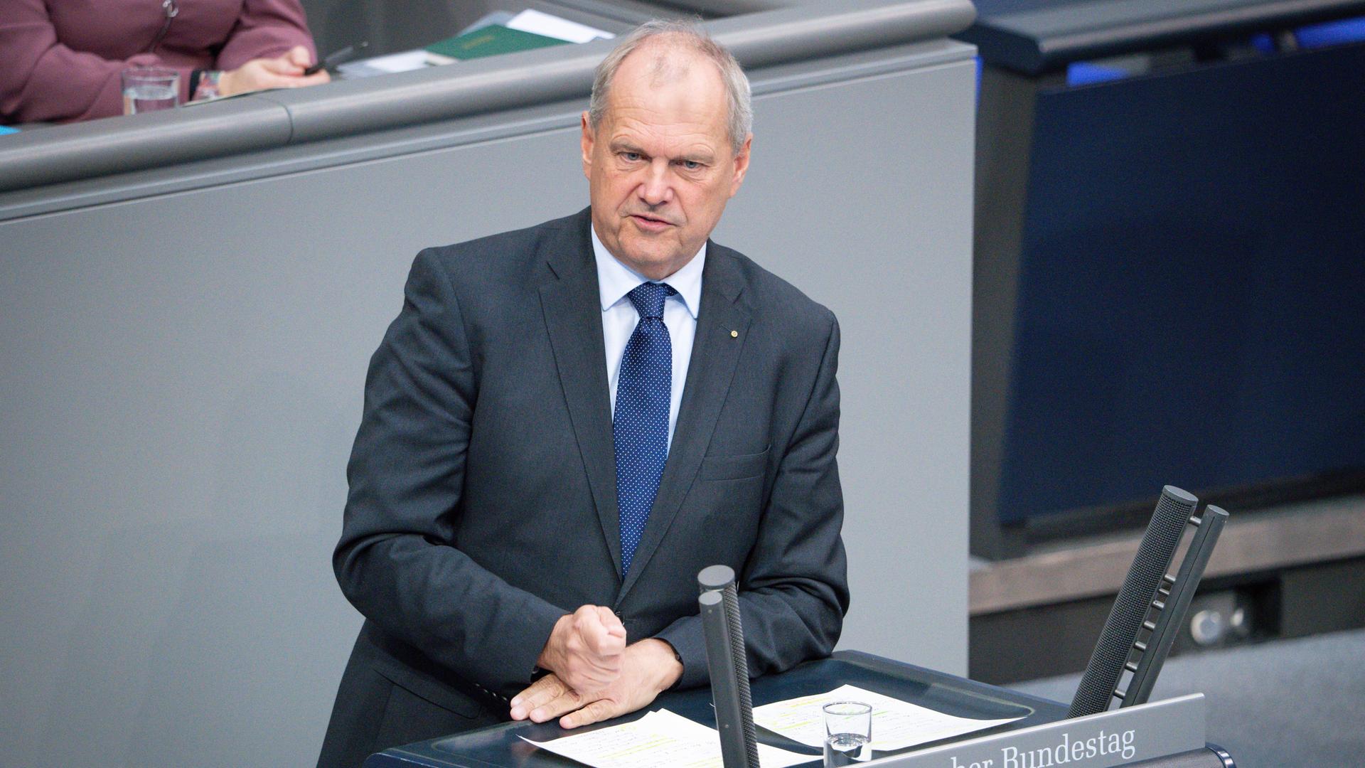 Der CDU-Politiker Fritz Güntzler steht im dunklen Anzug an einem Rednerpult im Bundestag und spricht. Er hat seine Hände auf den Unterlagen, vor ihm stehen Mikrofone und ein Wasserglas.