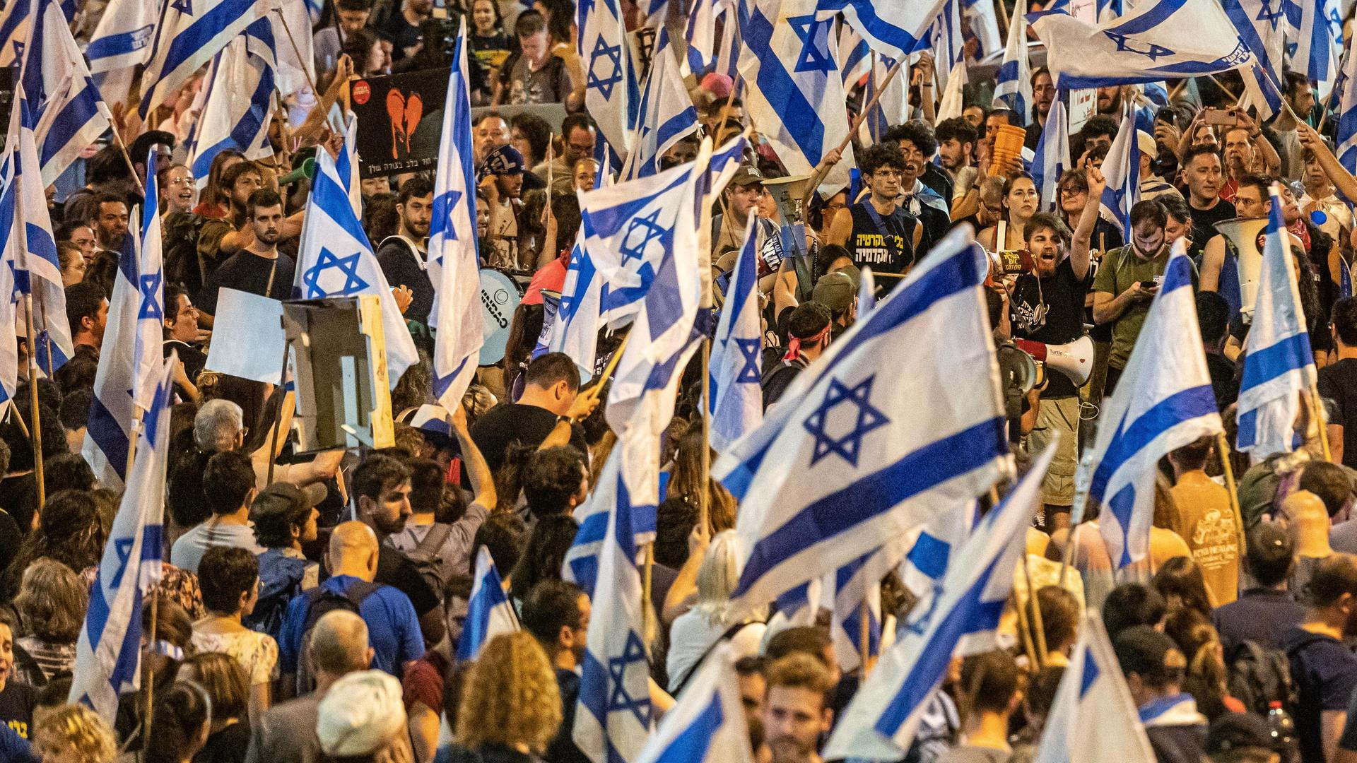 Zehntausende Israelis protesiteren or der Knesset in Jerusalem und schwenken Fahnen. 