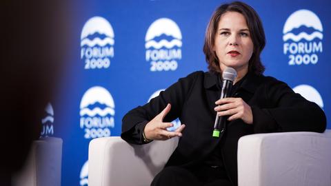 Bundesaußenministerin Annalena Baerbock sitzt auf einem Podium.