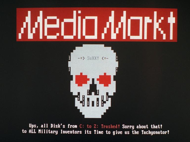 Screenshot von besagtem Computervirus: Ein grob gepixelter Totenkopf mit dem Schriftzug „SuXX!“ auf der Stirn. Darunter die Drohung auf Englisch, dass nun alle Laufwerke gelöscht werden.