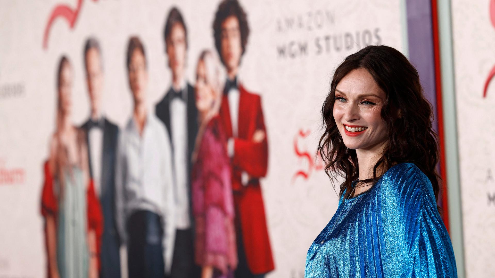 Musikerin Ellis-Bextor steht bei der Filmpemiere vor einem Plakat des Films "Saltburn" und lächelt. Musikerin Ellis-Bextor steht bei der Filmpemiere vor einem Plakat des Films "Saltburn" und lächelt.