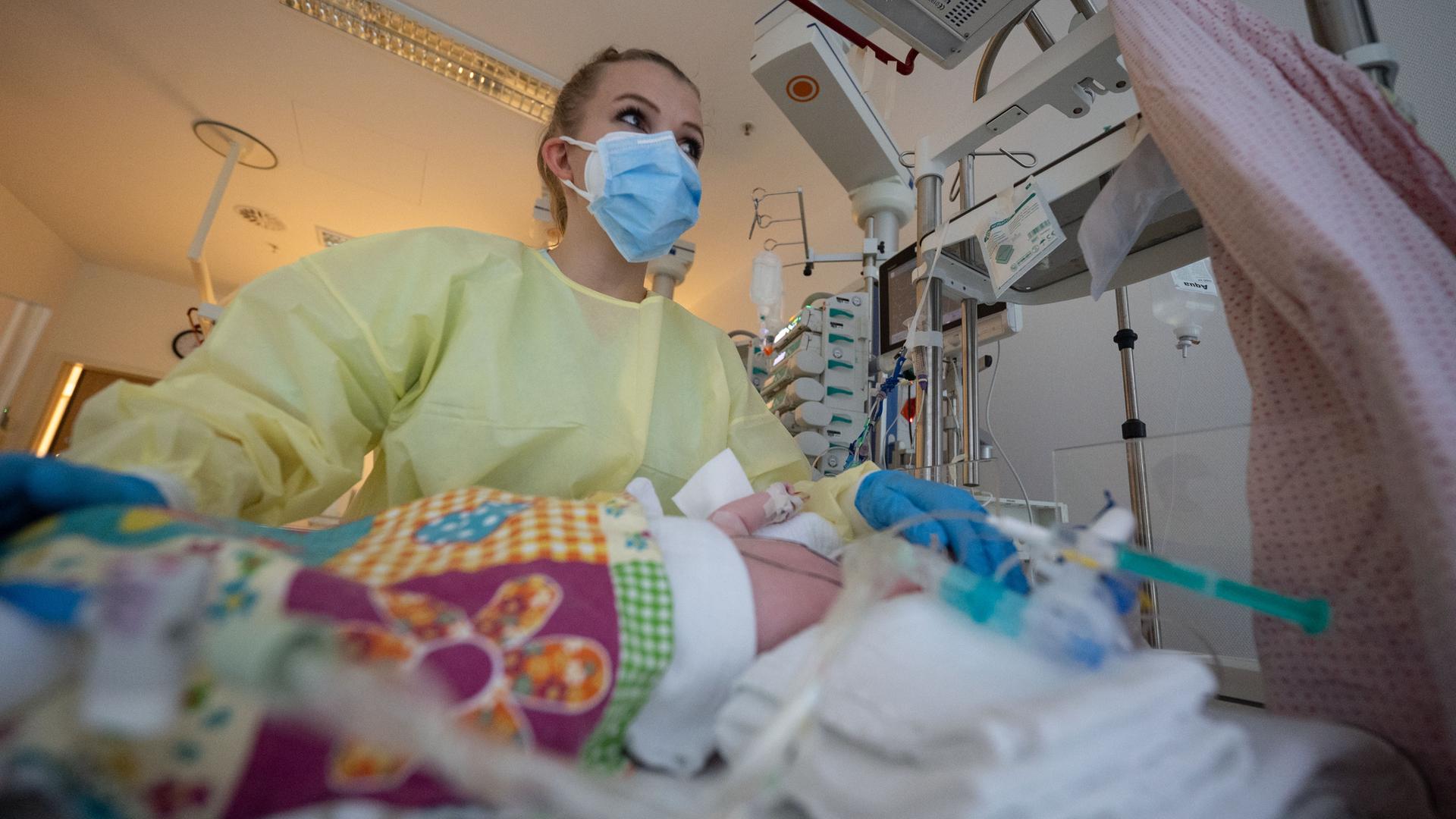 Eine Intensivpflegerin versorgt auf der Kinder-Intensivstation ein am Respiratorischen Synzytial-Virus erkranktes Kind, das beatmet wird.