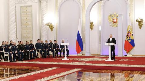 Russlands Präsident Putin zeichnet Soldaten mit der Gold Star Medaille aus. Sie sitzen in Reihen auf Stuhlen, Putin steht hinter einem Rednerpult.