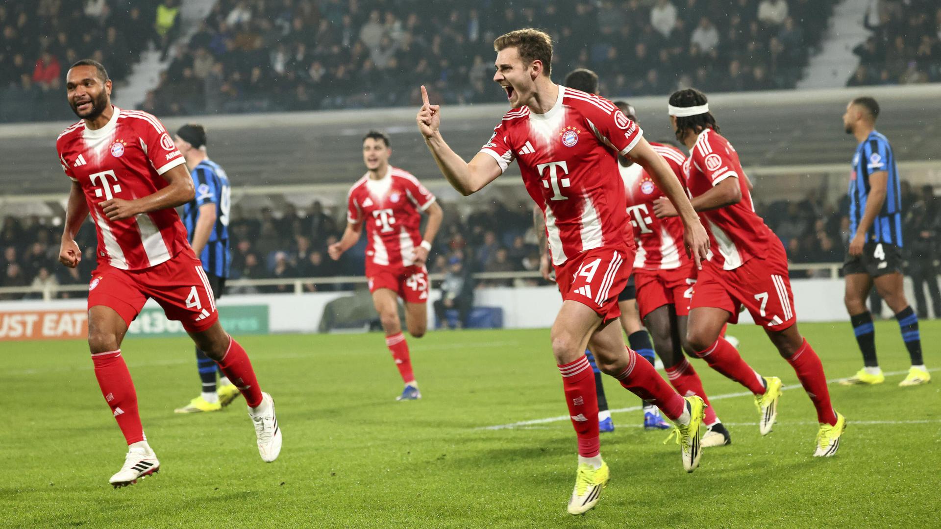 Josip Stanisic und andere Bayern-Spieler rennen jubelnd über den Fußballplatz.