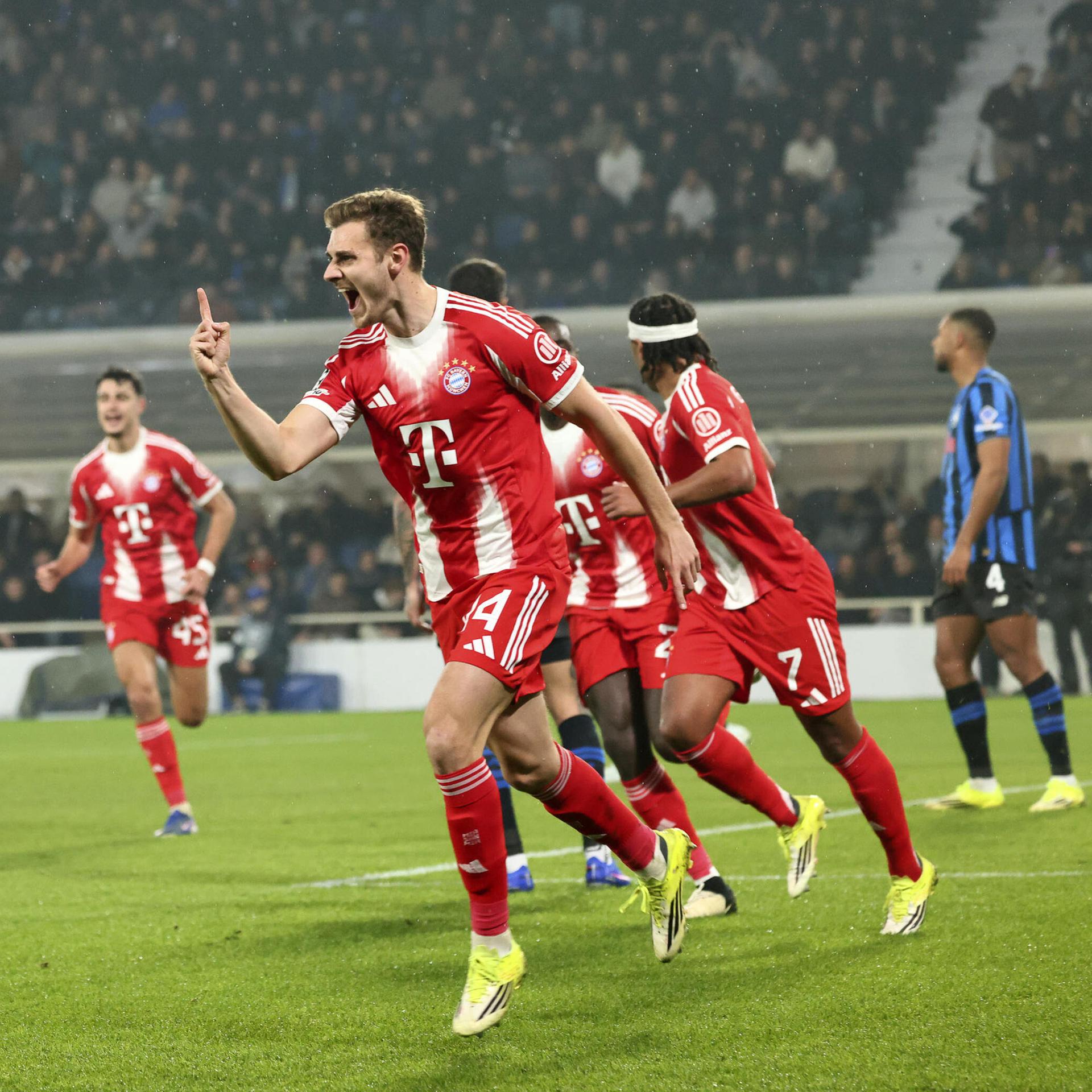 Josip Stanisic und andere Bayern-Spieler rennen jubelnd über den Fußballplatz.