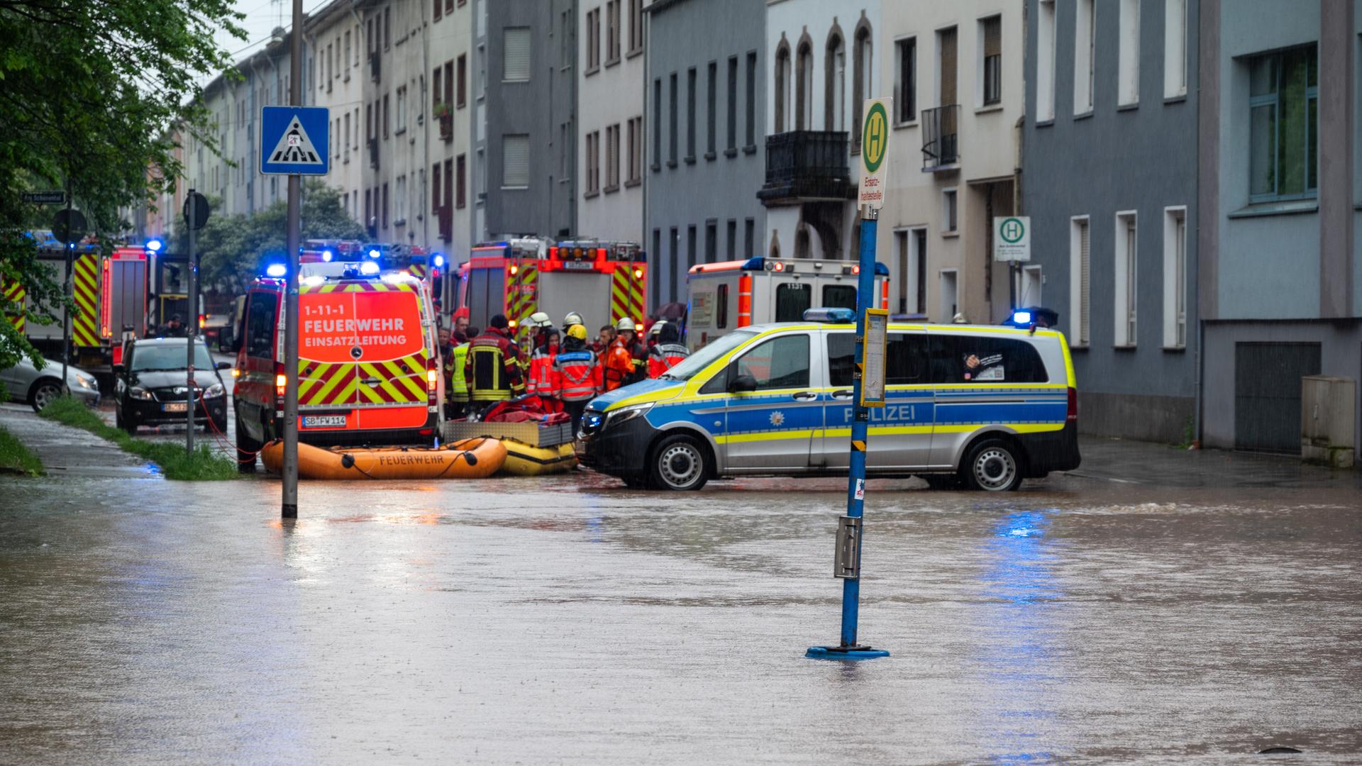 In Saarbrücken steht nach starken Regenfällen die Fischbachstraße unter Wasser. Feuerwehr und Polizei haben Absperrungen errichtett.