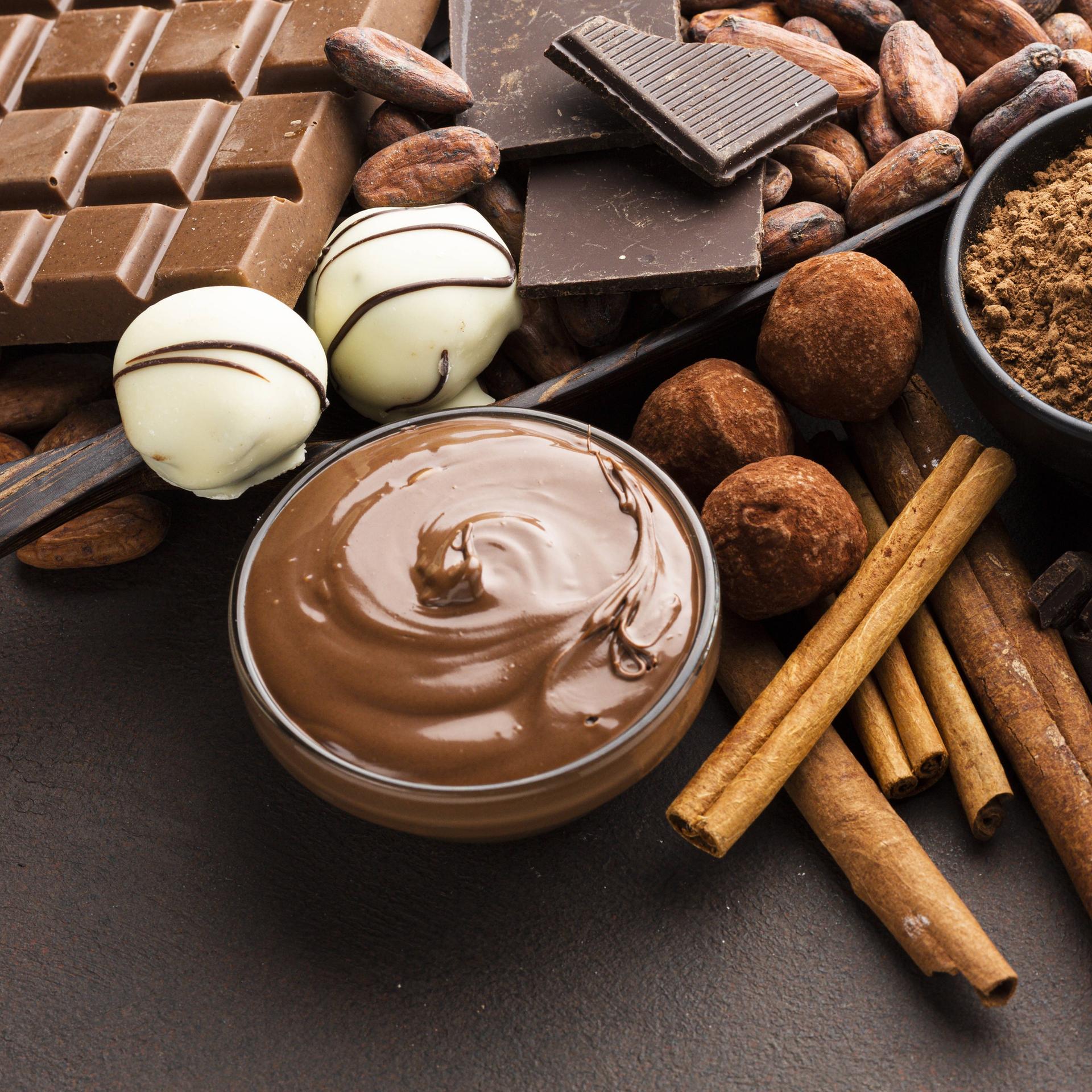 Eckige und runde Schokoladenstücke und Schokoladenpudding stehen auf einem Tisch.