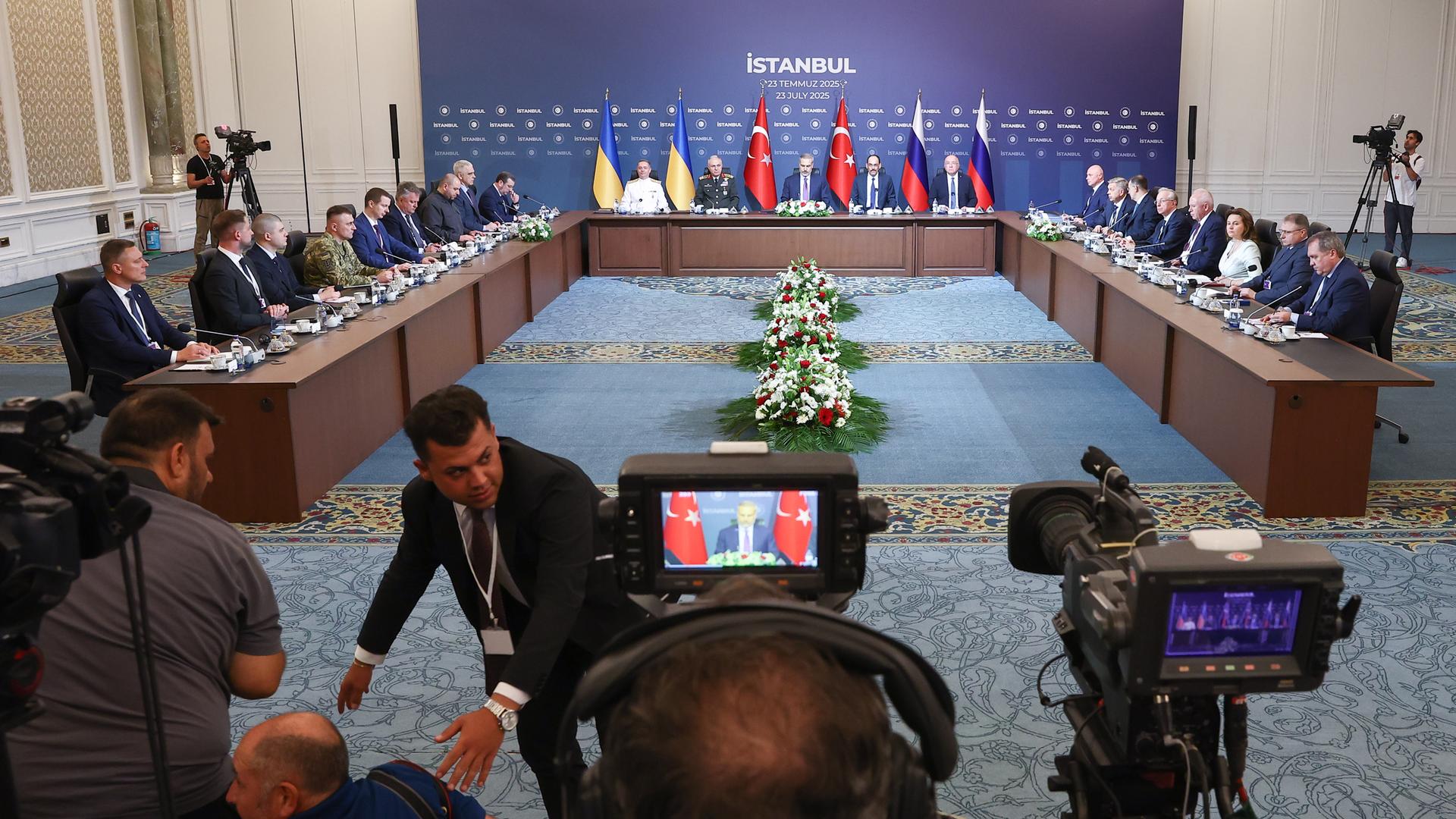 Die dritte Runde der russisch-ukrainischen Verhandlungen in Istanbul. Beide Delegationen sitzen sich in einem großen Raum gegenüber. Davor haben Medien Kameras aufgebaut.