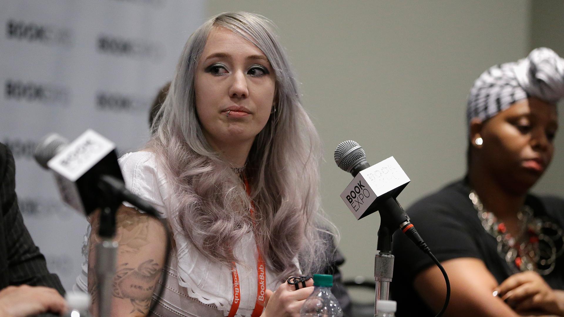 Zoë Quinn sitzt während einer Pressekonferenz auf einem Podium.