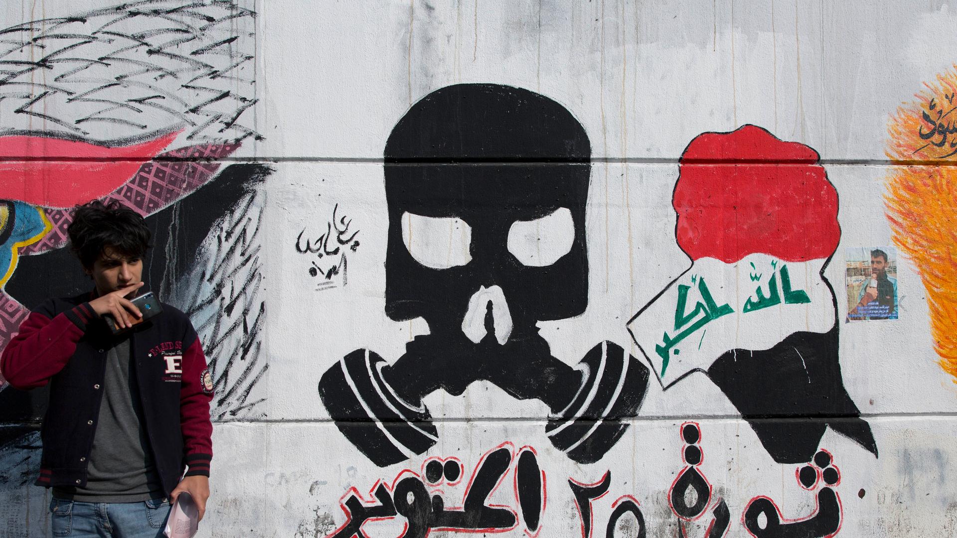 An Iraqi youth stands by a mural with Arabic that reads, "October 25th revolution, God is great," in Baghdad, Iraq, Sunday, Dec. 8, 2019. (AP Photo/Nasser Nasser) An Iraqi youth stands by a mural with Arabic that reads, "October 25th revolution, God is great," in Baghdad, Iraq, Sunday, Dec. 8, 2019. (AP Photo/Nasser Nasser)