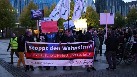 Teilnehmer einer Demonstration gehen mit Transparenten und Fahnen, darunter von der "Freien Jugend", eine Straße entlang