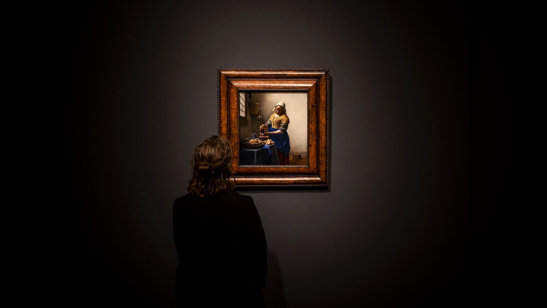 Eine Frau betrachtet Johannes Vermeers Gemälde "Dienstmagd mit Milchkrug".