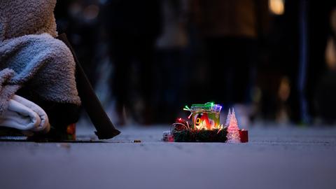 Ein Obdachloser bittet mit einer weihnachtlich gestalteten Spendendose um Geld.