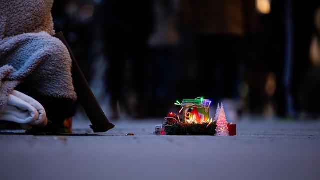 Ein Obdachloser bittet mit einer weihnachtlich gestalteten Spendendose um Geld.