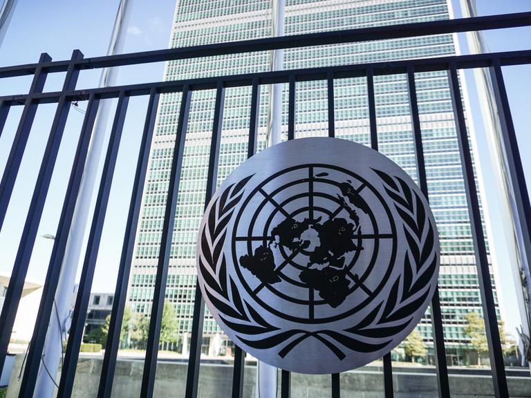 Ein Schild mit dem Logo der Vereinten Nationen vor dem UN-Hauptquartier in New York.  