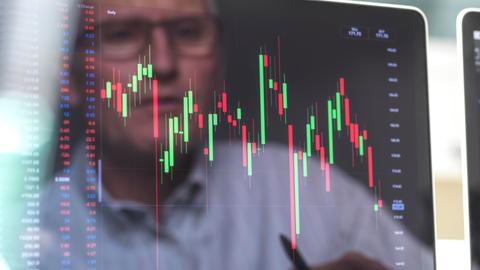 Börsianer spiegelt sich in einem Bildschirm, der mann betrachtet die Grafik eines Börsenkurses