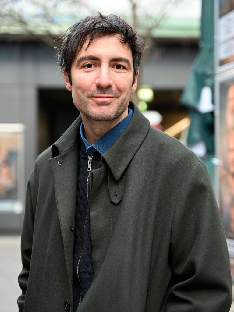 İlker Çatak trägt einen grauen Mantel und posiert im Freien für ein Porträt.