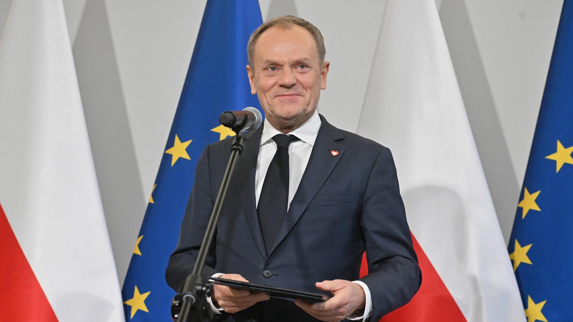 Der polnische Minister-Präsident Donald Tusk steht vor vor polnischen und europäischen Flaggen.
