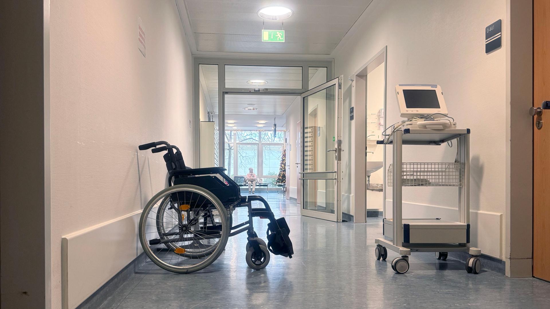 Ein leerer Rollstuhl steht in einem Flur von einem Krankenhaus.