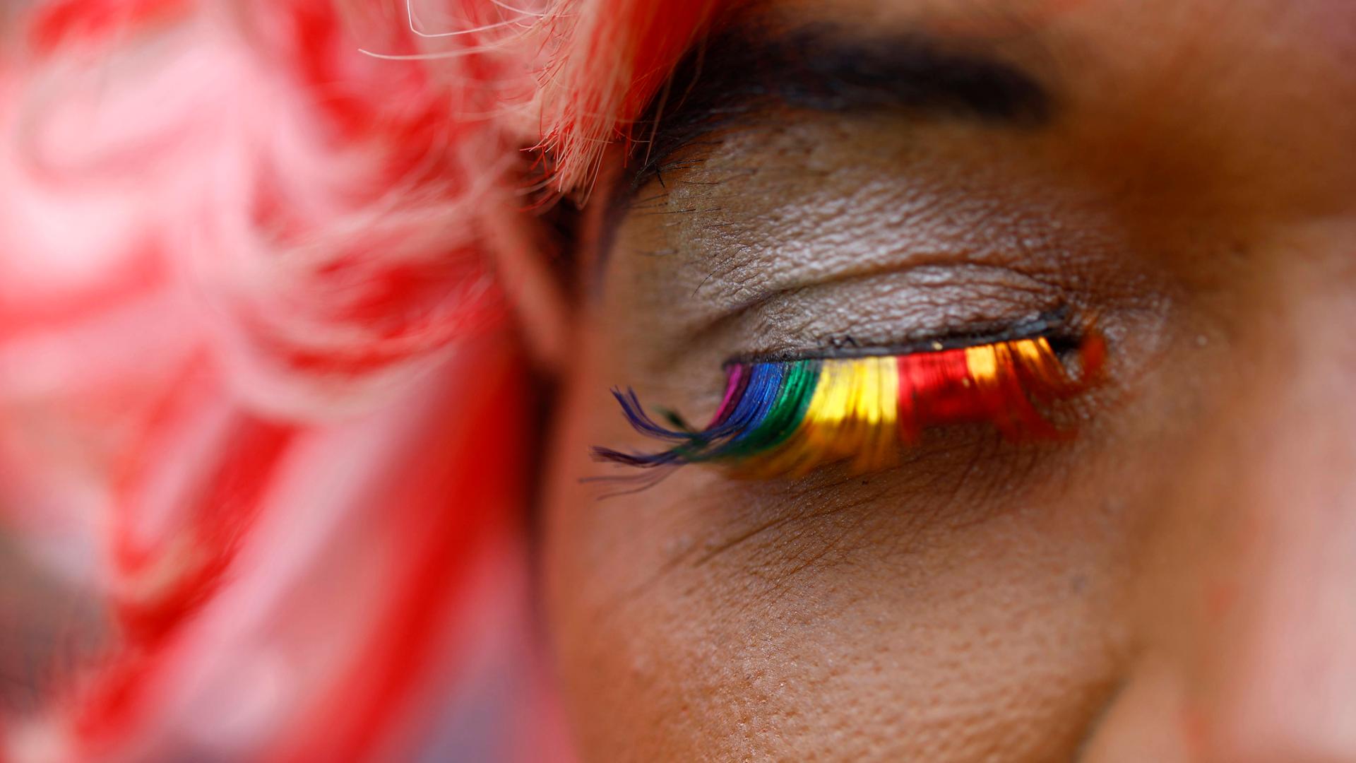 Nahaufnahme eines Auges mit False Lashes in Regenbogenfarben.