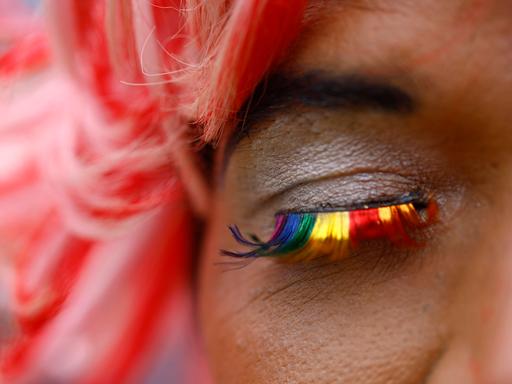 Nahaufnahme eines Auges mit False Lashes in Regenbogenfarben.