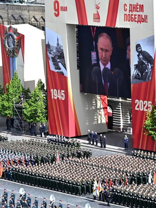 Unzähliche Soldaten marschieren, darüber zeigt eine große Videoleinwand Putin: Militärparade zum 80. Jahrestag des Sieges über Nazideutschland in Moskau.