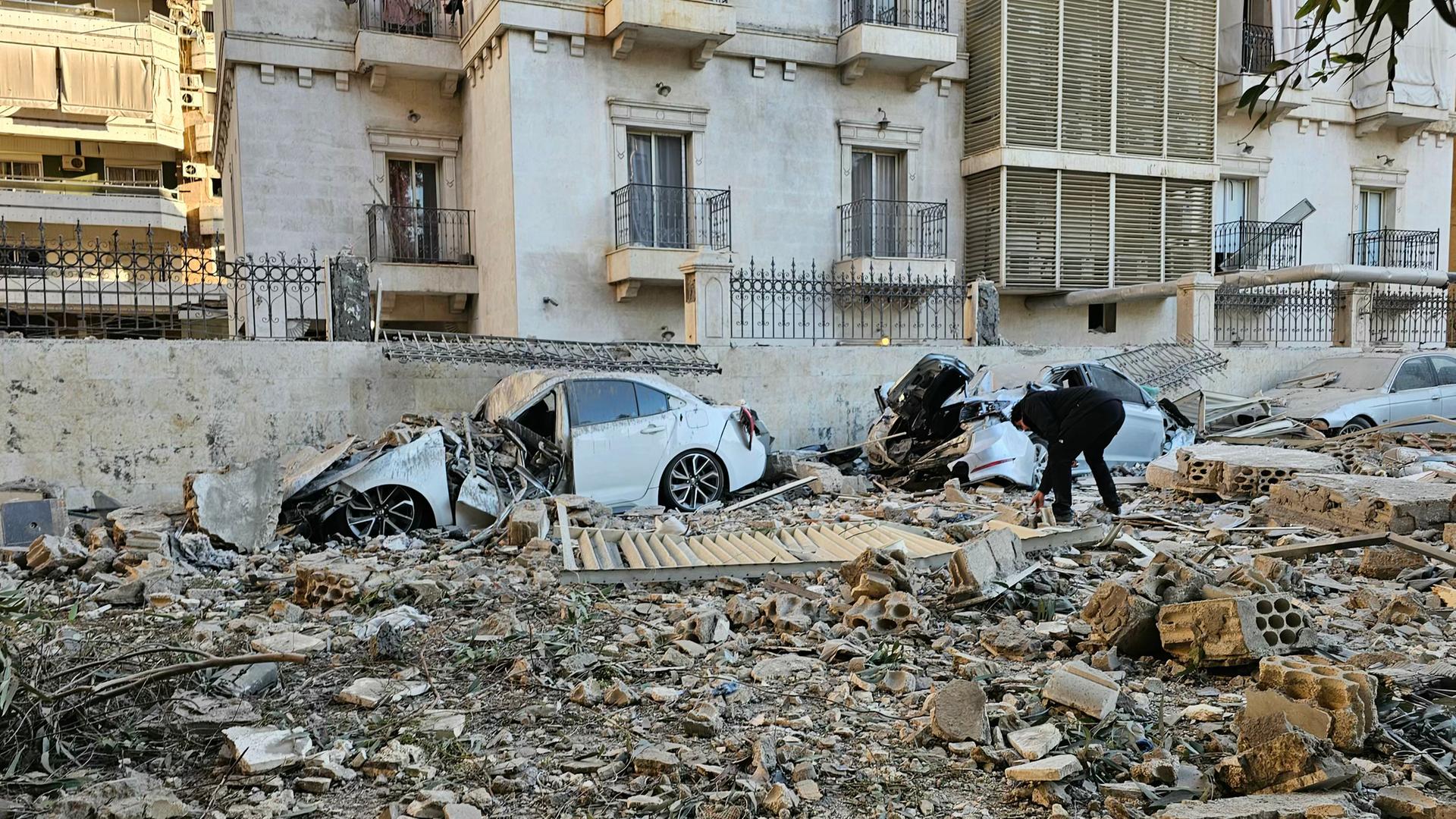 Ein Mann untersucht die Autowracks und Häusertrümmer nach dem israelischen Angriff in Beirut.
