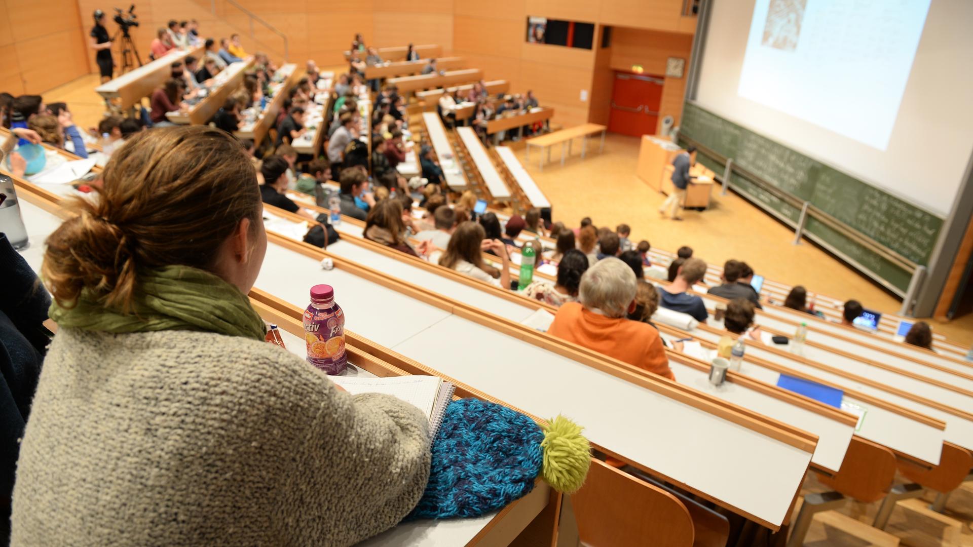 Von oben sind Studierende in einem tribünenartigen Vorlesesaal einer Universität zu sehen