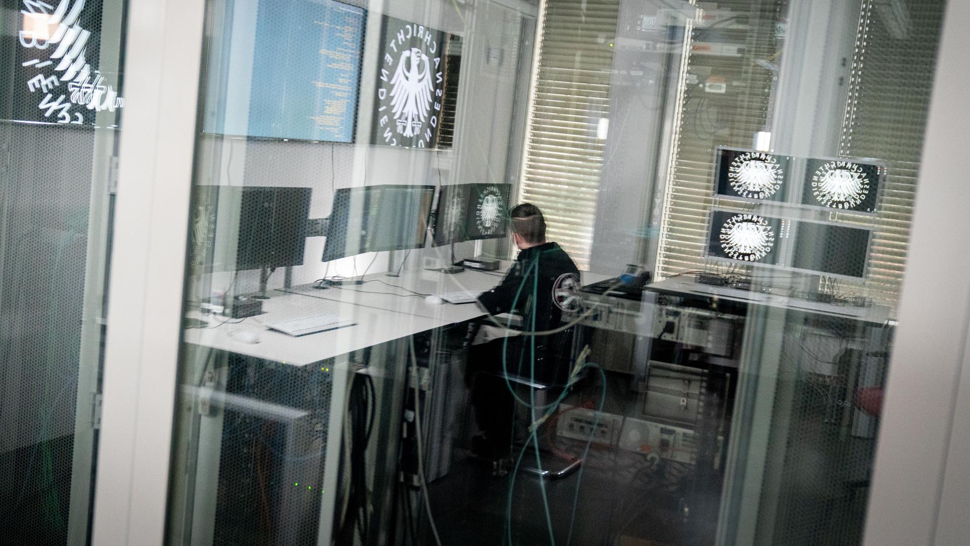 Ein Informatiker und Hacker spiegelt sich in der Scheibe zu einem Serverraum des Bundesnachrichtendienstes (BND) in Berlin
